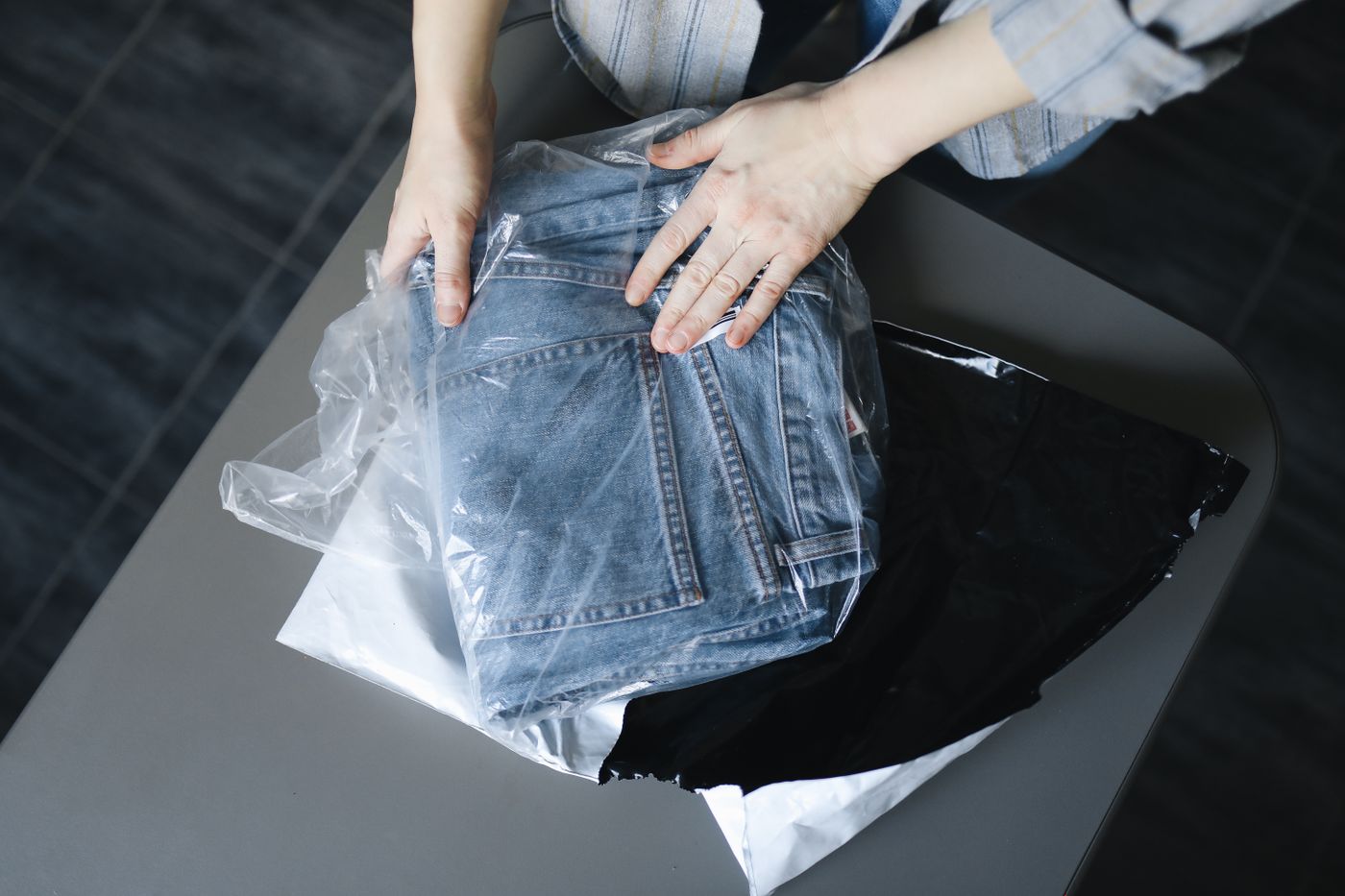 Penjual olshop mengemas celana jeans ke dalam kantong plastik