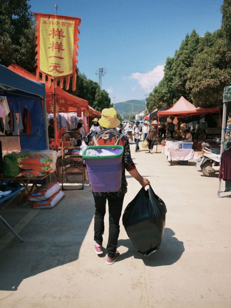 Shopper carrying a black plastic bag at a market