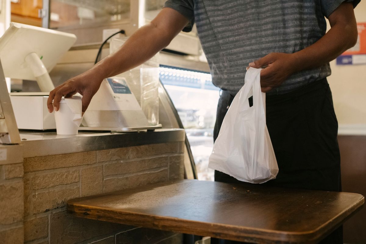 Pelanggan mengambil pesanan takeaway dalam kantong plastik putih